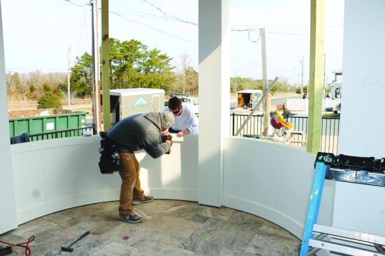 The top rails spring into place and the crew levels them using a laser level. Stainless steel screws hold them in place as well.