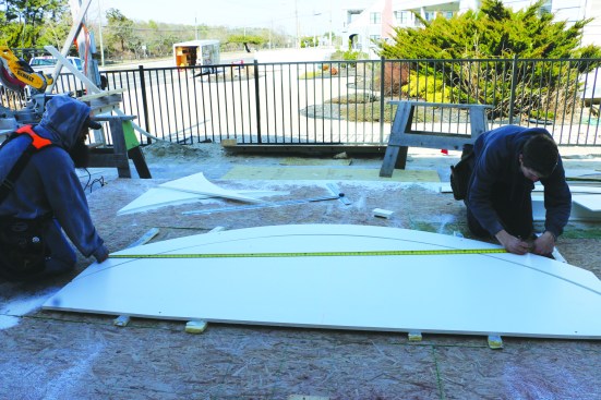 After measuring a straight line between the posts for each arc, the crew transfers the measurement to the radiused cap.