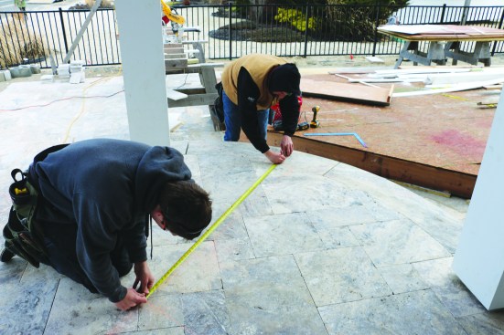 After laying out where the 2x4 framing meets the posts, the crew measures the distance from the pivot point to the layout. While one person holds the end of the tape at the pivot point, a second person scribes both the outside radius ...