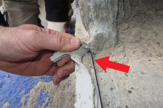 A continuous bead of sealant at the saw-cut-in flashing (red arrow) may have helped keep bulk water outside during lighter rain events, but when it rained long and hard enough, water draining down behind the stone veneer would simply run down past the roof and into the ceiling below.