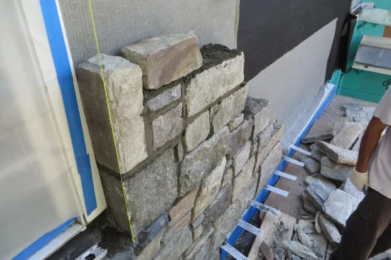 The exposed face of coated copper flashing was protected with blue tape, then the water management layers were installed on the wall.