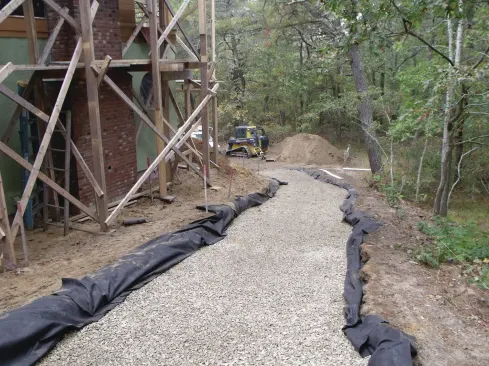  After excavating down about 18 inches and digging trenches across the driveway every 10 feet for drainage, we covered the whole thing with a nonwoven landscape filter fabric and 12 inches of 3/4-inch washed stone.