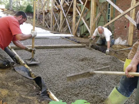 While the machine was being refilled, crew members compacted the edges and screeded the surface flat with a straightedge. 