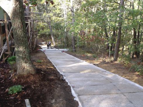 After each batch of concrete had been screeded, edged, and densified, workers immediately unrolled a plastic sheet that was at the ready, and pressed it into the fresh, wet concrete to keep it from curing too quickly.