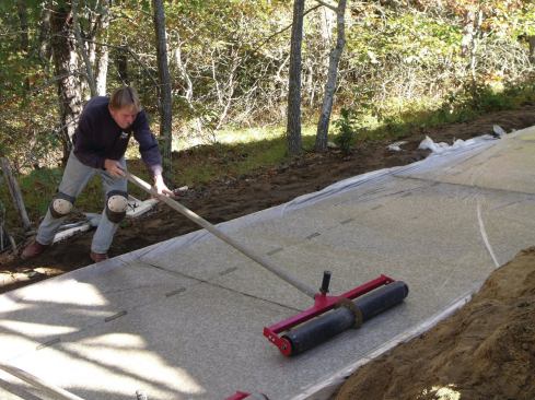 To cut a control joint, a crew member carefully placed a rolling joint tool on top of the plastic-covered wet concrete and pushed the roller across the driveway from one side to the other.