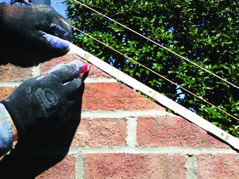 Using a brick-spacing ruler, he laid out even spacing of the rowlocks.