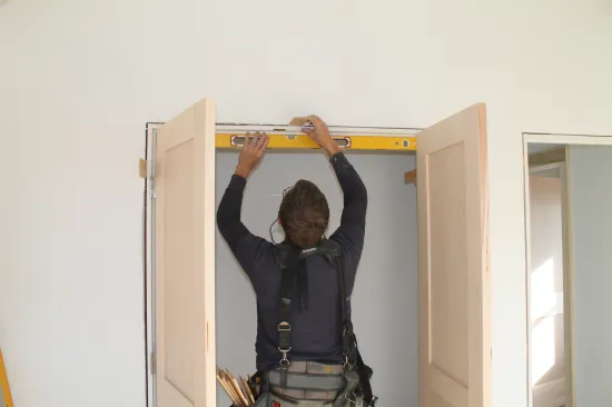 Using a level as a straightedge, shim the  head jamb until it is perfectly straight. Don't nail through the shims, they will be removed when the casing is installed to hold the jamb straight.