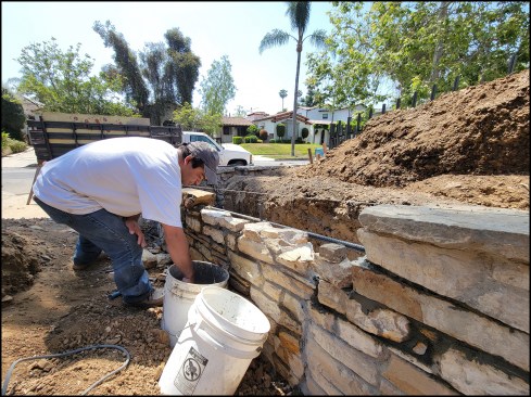 A crew member rebuilds a collapsed portion of a stone retaining wall located in a historic district of Los Angeles.