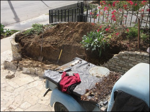 The middle third of a leaning, unreinforced stone retaining wall collapsed during excavation by the homeowner.