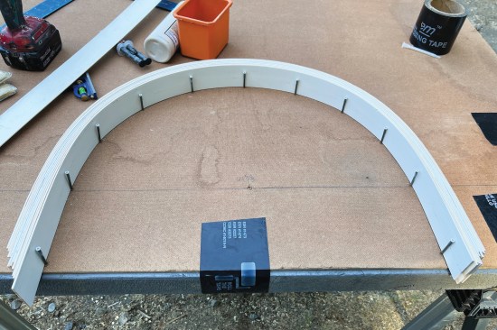 Pieces of clear pine stock were cut to the jamb depths, then ripped them into thin strips on a table saw. The ripped strips were glued up and bent them along the radius lines; the finish screws held the laminations in place. The strips were run long and later cut along the arch’s spring line.