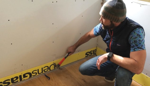 To provide the durability needed to protect walls from mops, vacuum cleaners, and skateboards, the author uses DensGlass or Glass-Mat for the first 6 to 8 inches above the floor.