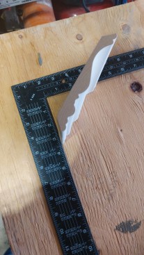 With an offcut of the crown squared up into the corner of a framing square, we can measure how far down it will sit from the ceiling.