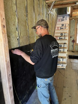 The steel-stud cavity is filled with mineral-wool insulation before the MLV sheet is installed.