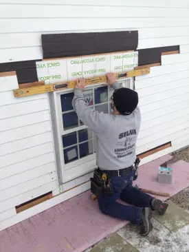 After positioning the window in the opening, Manny checks the top of the window for level.