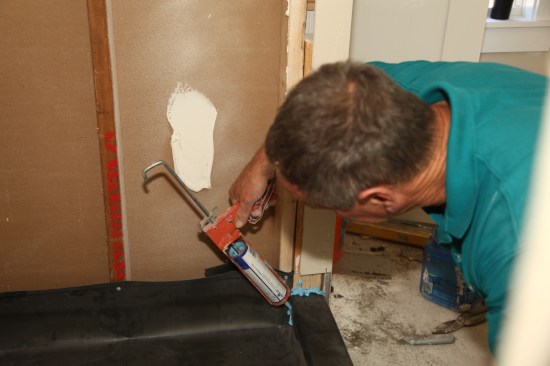 Apply a generous bead of sealant to the joint underneath, as well as to the overlapping piece and then press it into place to seal the corner. 