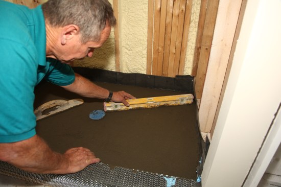 Screed the final surface perfectly flat with no voids. For this step, a level works well to make sure that the surface of the mud base is sloped at around 1/4 inch per foot toward the drain. 