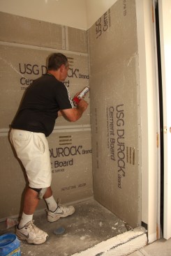 After the backerboard is nailed in, seal the corners with a bead of silicone caulk.