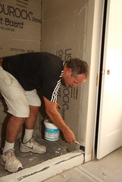 If there are areas where the tile will overlap onto a finished wall surface—like the sides of the shower entry on this project—brush a liquid waterproofing membrane, such as Hydro Ban, on the overlapping area. 