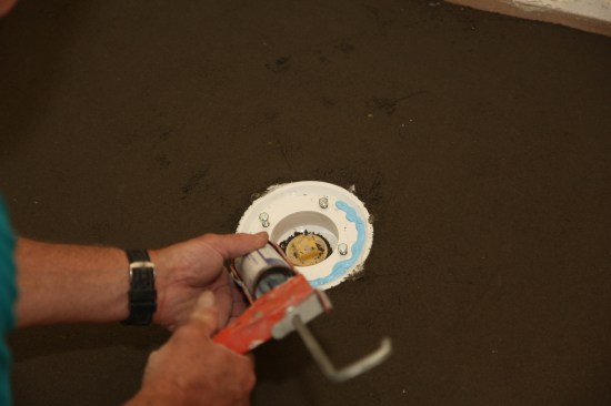 The final step before cutting and fitting the membrane is applying an elastomeric sealant, such as NobleSealant 150, around the drain assembly. This will create a seal between the membrane and the drain.