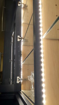Light tape mounts behind a cabinet face frame and glass shelves let light shine through to more than one level.