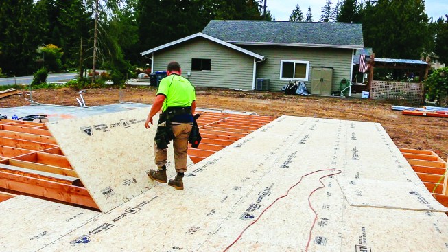 A crew member drops a sheet into place, using one foot to keep it from sliding away.