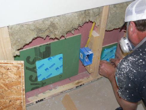 Re-sealing the repaired OSB air barrier layer after removing and replacing wet cellulose insulation. After the repair, the house scored about 0.27 ACH50 on a repeat blower door test for Passive House certification.