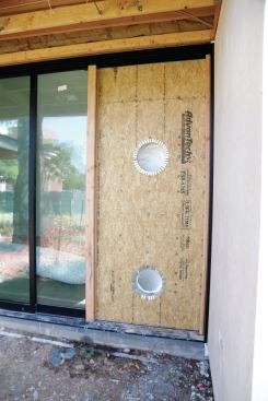 The ducts for the portable AC units are sent through a sheet of OSB with two holes cut in it.