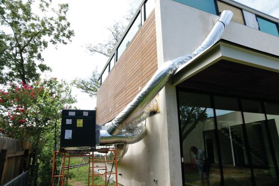 A 5-ton heat-pump for heating and cooling is set up on staging outside the house, and unlike the smaller units, doesn't need to be shuffled around the jobsite. Shown here is the supply duct.
