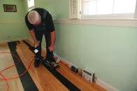 After the first three courses are installed, there is enough room to use a power nailer. This particular nailer has a protective plastic pad that keeps the nailer from scratching the floor finish.