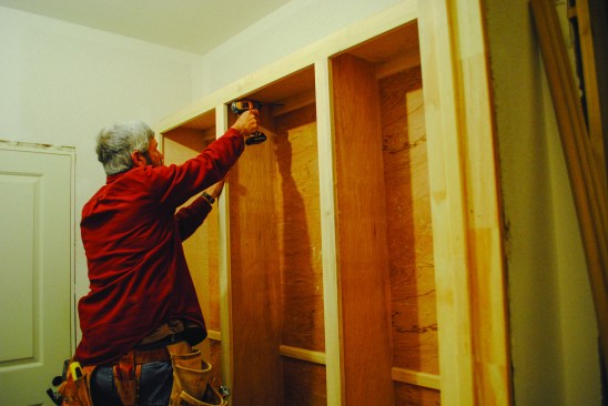 Combined unit. The base section is set in place first, then the upper section sits on top. Screws driven through the upper cleat and into the wall framing secure the upper cabinet in place.