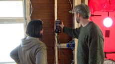 Architect Rachel Conly watches as Harvey Johnson adjusts the settings of the blower door control.