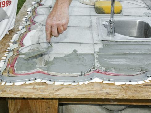 I used a trowel and damp sponge to spread a 1/8-inch-thick layer of latex thinset mortar over the concrete base to ensure that the mortar bed would stay bonded to the base.