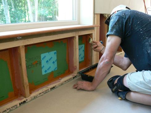 EcoCor carpenter Richard Perry seals the joint between the fresh ZIP System patch and the existing OSB sheathing air barrier using Prosoco fluid-applied membrane (the same material used earlier to address air leakage through the face of the OSB).