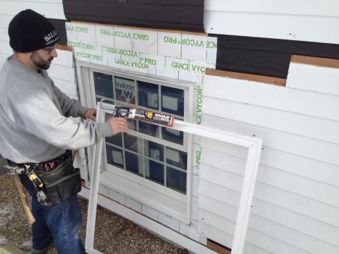 Manny applies a bead of caulk to the back side of the prefabricated window trim before setting it into place.