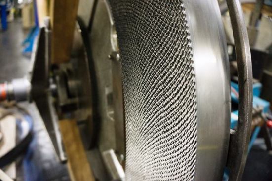 This coil of bi-metal material, has been placed on a reel and is about to be fed into the machine that sets the teeth.