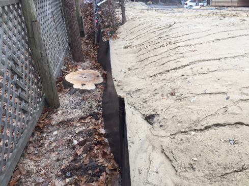 As another erosion control method, silt fencing is staked along neighboring properties with the bottom 6 inches of it buried. Here, it's clearly doing its job after many days of torrential rain.