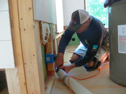 EcoCor carpenter Richard Perry screws a ZIP sheathing patch over the hole in the double wall air barrier layer after removing wet insulation and drying the wall assembly.