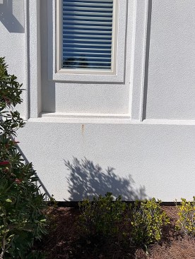A rusting fastener was one sign that seemed to suggest water leaks around a window. But when the author was called in to perform a window leakage test, no leaks from the window units were detected. The rust stain is at the level of the bottom wall plate. The apron below that is covering the slab edge.