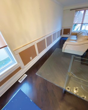 On a raised-panel style of wainscoting, rails form boxes, and profiled trim tops hardboard panels.