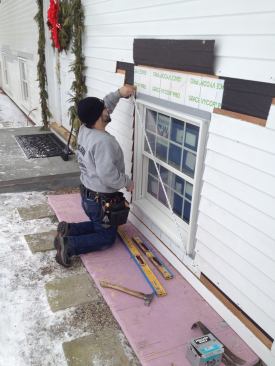 Before nailing the top corners, Manny checks the diagonal measurements of the window in both directions to make sure it's perfectly square.