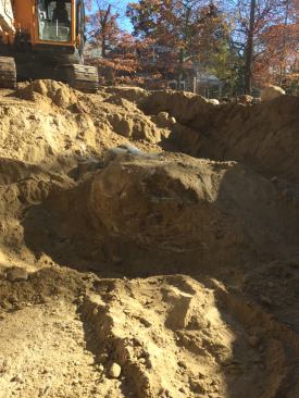 Excavation for the foundation reveals unusable soil filled with silt and clay. Almost 970 yards of material has to be trucked off site and replaced at this stage of the excavation. This huge boulder is part of the glacial tlll that was found below grade.