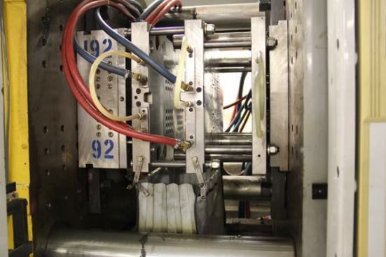 The vertical metal plates shown here are an injection mold, the “business end” of an injection molding machine. The machine brings the molds together, injects molten plastic, the plastic cools and solidifies, the molds come apart, and the plastic pieces fall out and are blown into a bag.
Click here for video.