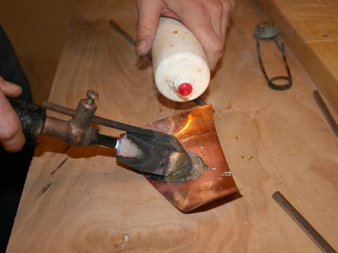 When it’s hot enough, “tin” the tip on a scrap piece of copper. Squirt some flux, and then melt some solder. Helpful tip: we put soldering flux into an empty, contact-lens solution cleaner in lieu of dipping a dirty flux brush into a large container of flux.