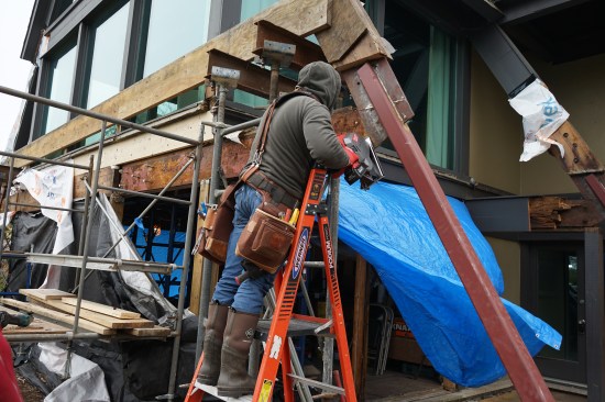 After removing the rotted ledger and grinding off the corroded bolts, the author made the first cut to sever the connection between the flitch plate spliced into the rafters and the plate sandwiched between the ledger and the rim joist.  