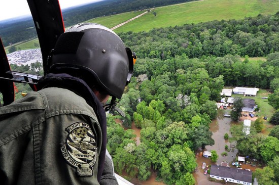 A Coast Guardsman looks out from an MH-65 Dolphin helicopter searching for stranded residents in Baton Rouge, LA on Aug. 15, 2016. Photo by Petty Officer 1st Class Melissa Leake (photo from the U.S. Department of Agriculture via Flickr).
