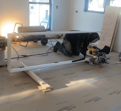 You may need to cut the jamb down in length before standing the unit in the rough opening for scribing. The author makes his jamb cuts using a miter saw on the floor. Without the door, the jamb legs will flop around, so he may attach a temporary stretcher 12 inches up from the bottom of the unit. In the photo above, he uses a framing square as a stretcher—a fast solution that works for a 2'-0" door.
