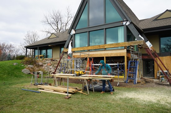 The author planed 2x10 stock to pack out the space between the new rim joist and the face of the new beam. It was much quicker and neater to plane down this material than it would have been to cut back all the floor joists to reposition the rim joist in relation to the windows. 