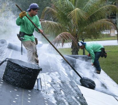 The hot tar is spread one course of asphalt roofing at a time and the 90-pound membrane is quickly applied before the tar cools.