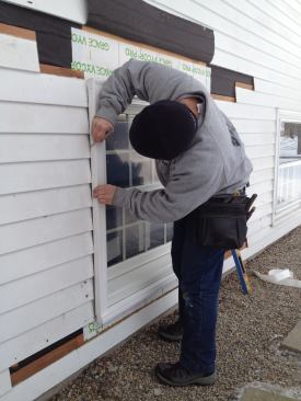 To save time and money, the original siding was kept in place for the installation. To fit the exterior trim, Manny holds the molding in place and scribes a line along the ends of the siding boards.
