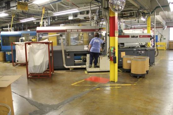This gal operates multiple injection molding machines. As pieces are finished they are blown through the PVC pipe and into the bag hanging from the red metal frame to the left. When the bag is full it will be hauled to the assembly area.